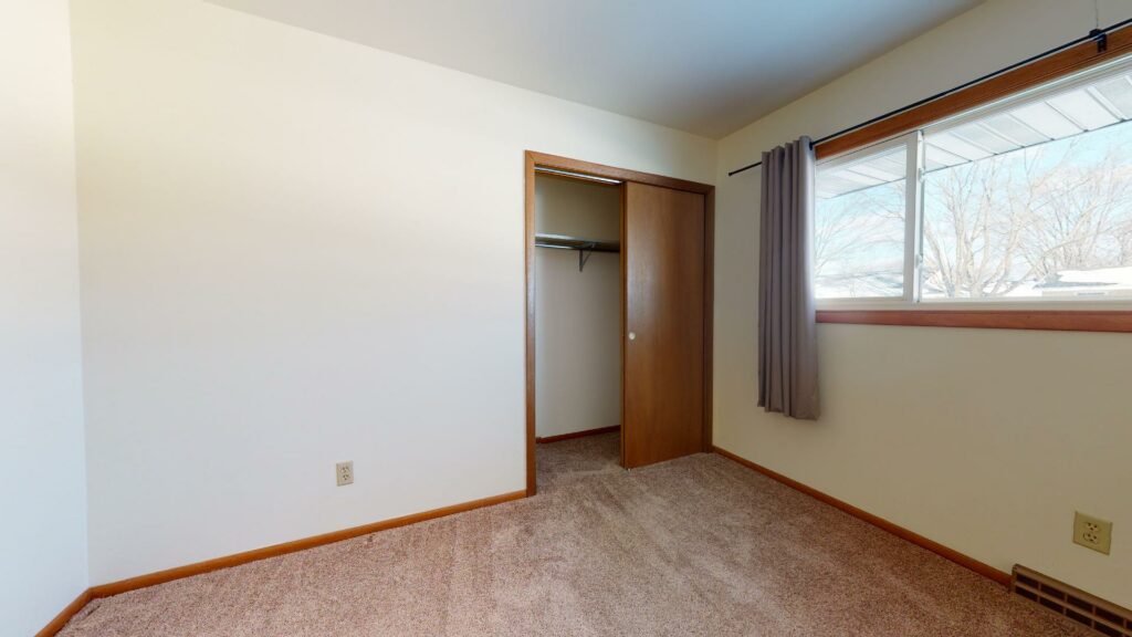 carpeted bedroom with large window and closet