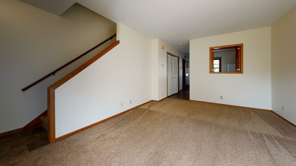 carpeted living area adjacent to staircase to upper floor
